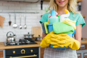 Professional cleaner holding eco-friendly cleaning supplies in a kitchen – A&D Cleaning Solutions, house cleaning Canterbury.